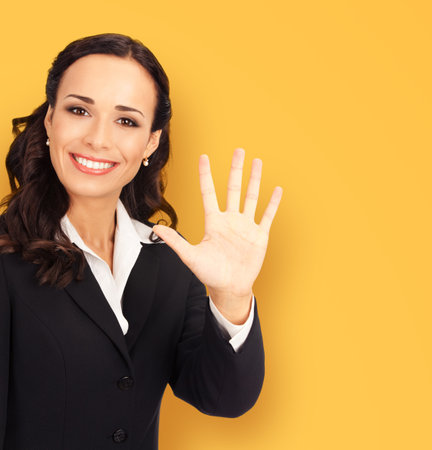 Ad concept image - happy smiling brunette businesswoman business woman executive person wear black confident suit, show five fingers hand sign gesture, isolated over orange yellow wall background.の写真素材