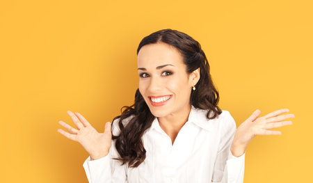 Wow! Portrait image of excited smiling positive business woman raise hands, isolated against yellow background. Happy gesturing cheerful smile woman. Dental care ad concept.の写真素材