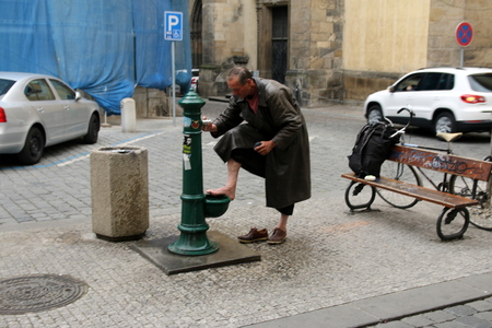 Homeless person washing his feet on the street in Pragueのeditorial素材