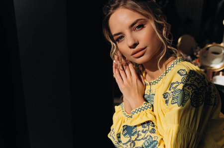 A girl in traditional Ukrainian clothing on black background. A young Ukrainian woman is sitting in a room in traditional national clothes. Ukrainian national clothing style.の写真素材