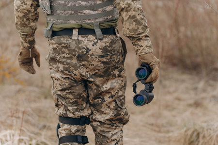 a soldier in camouflage holds binoculars. military man holding binoculars. soldier in the fieldの写真素材