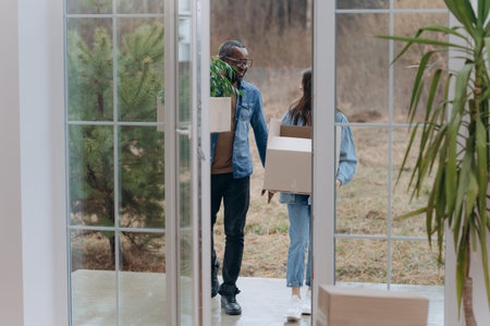 A young couple moves into a new house. an African-American man and his wife carry boxes into a new house. a family in a new houseの写真素材