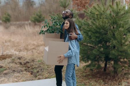 A happy young family is moving into a house. A black man and woman are holding cardboard boxes for moving, smiling. moving boxesの写真素材