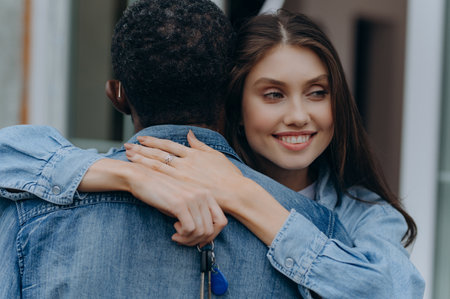 Closeup of young couple holding hands and new house key. Mortgage, real estate conceptの写真素材
