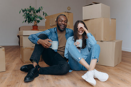 couple moving in house. interracial couple sitting near cardboard boxes