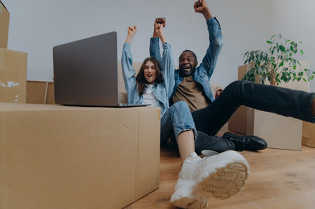 couple using laptop in their new house on moving day. a couple reacts emotionally to watching a video from a laptopの写真素材