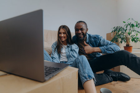 couple using laptop in their new house on moving day. a couple reacts emotionally to watching a video from a laptopの写真素材