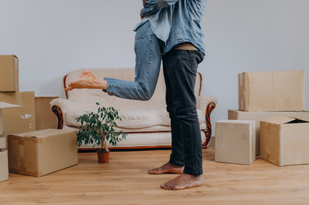 Close up of young man in jeans, wife surrounded by cardboard boxes, happy african american couple having fun, huggingの写真素材