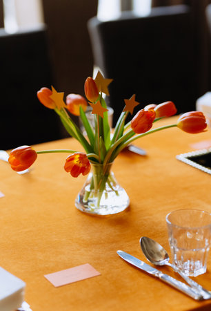 orange tulips on a decorated table with an orange tablecloth. bright decor. table decor for a child's birthdayの写真素材