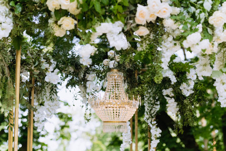 Vintage chandelier on the wedding arch. a close-up of a crystal chandelier hangs over a green photo boothの写真素材