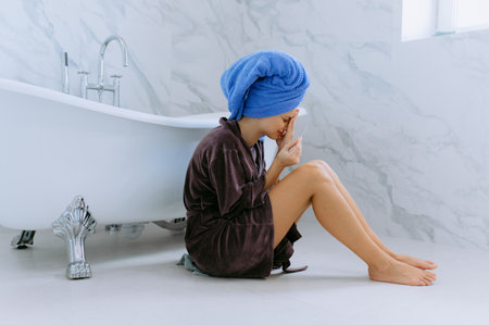 Unexpected pregnancy. Disappointed girl, pregnancy test. Woman in bathrobe looking at her pregnant test in toilet. Young disappointed woman sitting in bathtub and holding pregnancy testの写真素材
