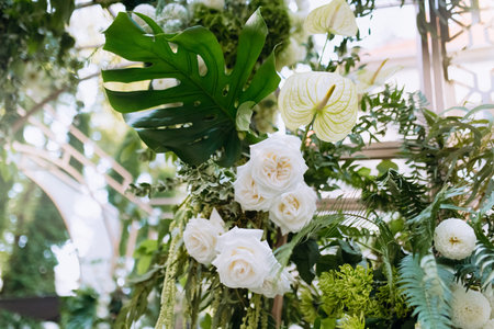 A fragment of a wedding arch decorated with flowers. The flower arrangement consists of different types of roses and green leaves. photo zone at the weddingの写真素材