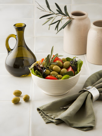green olives salad in a white bowl with olive oil and olive branchの素材