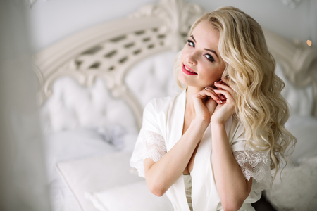 portrait of a blonde girl, bride, sits on the royal bed. Natural lightの写真素材
