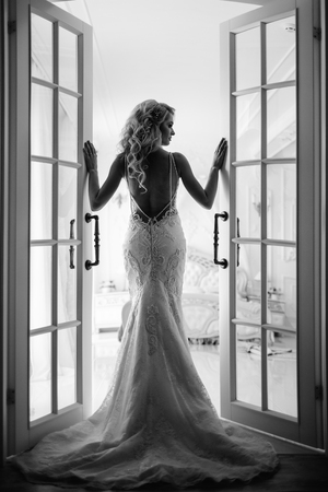 Wedding. Bride in a beautiful dress indoors in a white studio, like at home. The fashionable wedding style is taken in full length. Young attractive blond model with curly hair, like a brideの写真素材