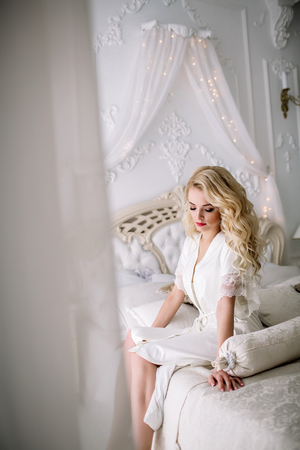 portrait of a blonde girl, bride, sits on the royal bed. Natural lightの写真素材