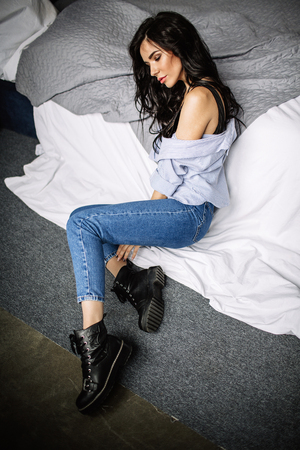 cute young woman sitting on the floor in blue jeans and blue shirt, fashionの写真素材