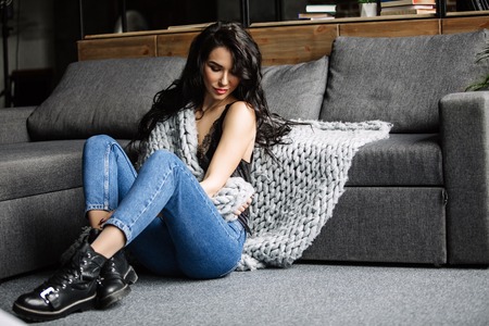 cute young woman sitting on the floor in blue jeans and blue shirt, fashionの写真素材
