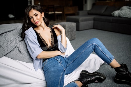 cute young woman sitting on the floor in blue jeans and blue shirt, fashionの写真素材
