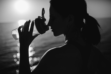 beautiful girl with sports forms sports on the beach, drinking water, jumping, running, doing different exercisesの写真素材