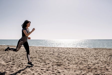 beautiful girl with sports forms sports on the beach, drinking water, jumping, running, doing different exercisesの写真素材