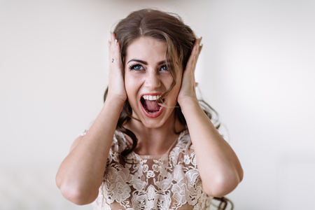 portrait of the bride shouts loudly covering his ears with his hands, furious. Natural light. Eyes openの写真素材
