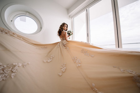 bride with long train in white room with panoramic sea views. Natural light. look out the windowの写真素材