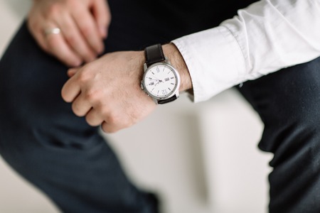 watch with white dial on the hand of a man in a white shirtの写真素材