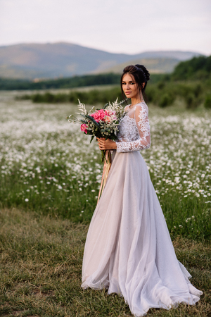 Beautiful woman enjoying daisy field, nice female lying down in meadow of flowers, pretty girl relaxing outdoor, having fun, happy young lady and spring green nature, harmony concept.の写真素材