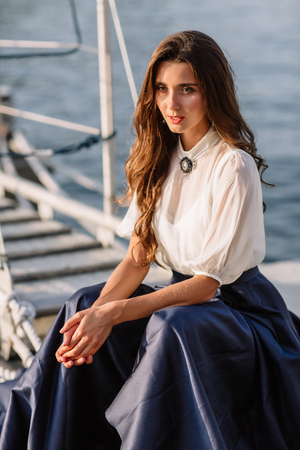 Beautiful girl walking on the pier by the sea near the yacht, boats in the blue long dressの写真素材