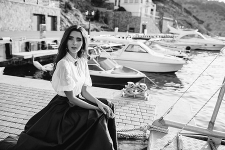 Beautiful girl walking on the pier by the sea near the yacht, boats in the blue long dressの写真素材