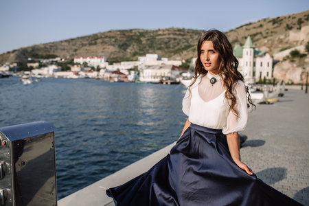Beautiful girl walking on the pier by the sea near the yacht, boats in the blue long dressの写真素材