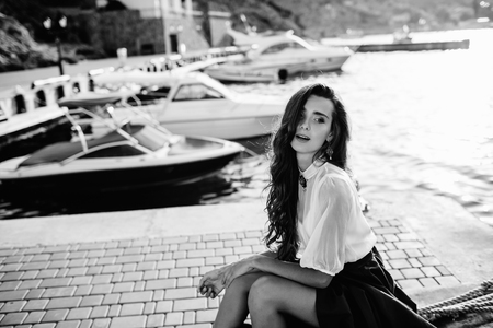 Beautiful girl walking on the pier by the sea near the yacht, boats in the blue long dressの写真素材