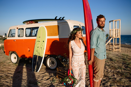 Happy surfers couple standing with surfboards on the sandy beachの写真素材