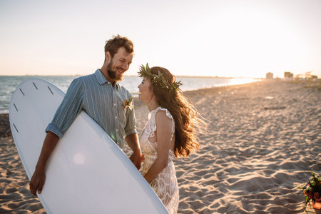 Happy surfers couple standing with surfboards on the sandy beachの写真素材