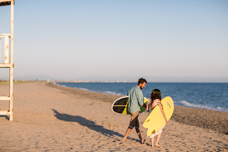 Happy surfers couple standing with surfboards on the sandy beachの写真素材