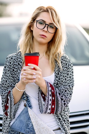 Young stylish woman in a city street near a white car.の写真素材