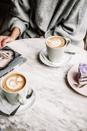 Female and man hands with cups of coffee on the background of a wooden tableの写真素材
