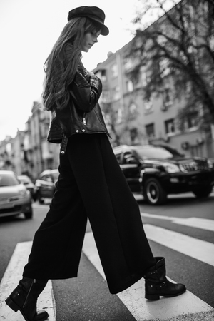 Beautiful girl with sunglasses. A model in a stylish wide-brimmed hat at a pedestrian crossing. Harmoniously similar clothes in gray tones. Street style shooting. Women's fashion.の写真素材