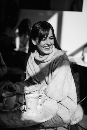 Beautiful girl laughs drinks coffee, teaの写真素材