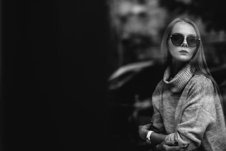 the girl at a table in a cafe drinks coffee, tea, looks out the window, is shot through glass, fashionの写真素材