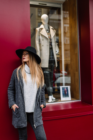 Portrait of a young beautiful fashionable girl wearing sunglasses. Model in a stylish black hat. Harmoniously similar clothes in gray tones. Street style. Women's fashion.の写真素材