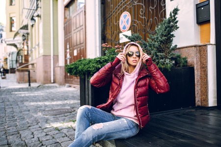 Stylish hipster girl in the retro jeans suit posing in front of the old building.の写真素材