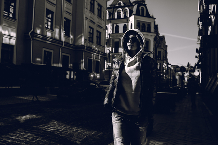 Street fashion concept - portrait of a beautiful girl sitting outside, blue jeans, sunglasses, hard lights, red jacket, autumn weatherの写真素材