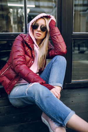Stylish hipster girl in the retro jeans suit posing in front of the old building.の写真素材