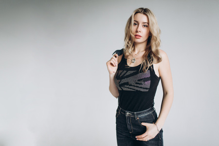 Portrait of a beautiful fashion woman, blonde, jeans, gray backgroundの写真素材