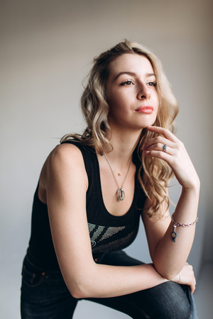 Portrait of a beautiful fashion woman, blonde, jeans, gray backgroundの写真素材