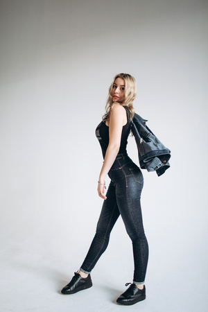 Portrait of a beautiful fashion woman, blonde, jeans, gray backgroundの写真素材