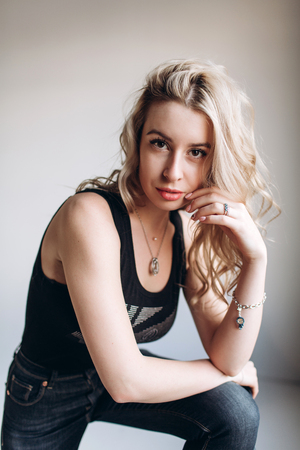 Portrait of a beautiful fashion woman, blonde, jeans, gray backgroundの写真素材