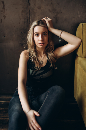 Portrait of a beautiful fashionable woman, blonde, jeans, brown backgroundの写真素材